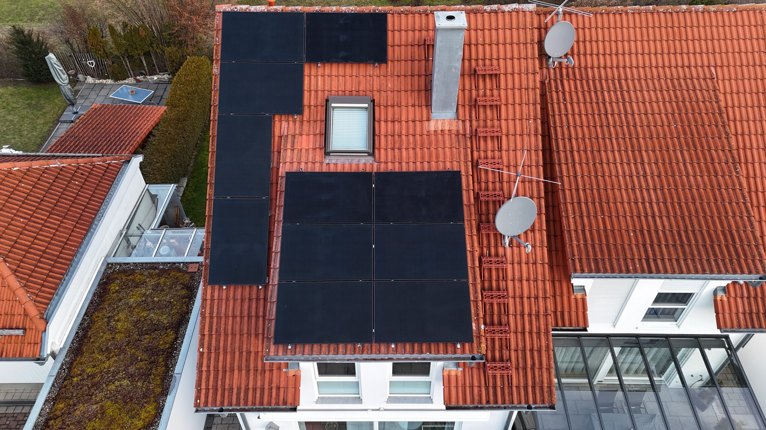 Drohnenaufnahme eines Einfamilienhauses in Neuffen mit neu installierter 5,23 kWp Photovoltaikanlage auf Hauptdach und Gaube, vollschwarze AIKO-Module von HUMMEL energize