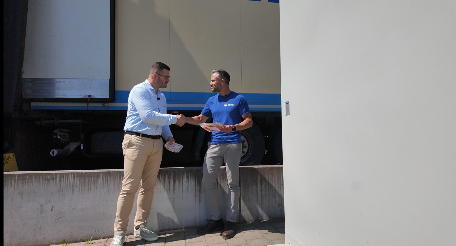 Handschlag zwischen Simon Marziale-Brenner und Alexander Hummel vor dem Speichersystem