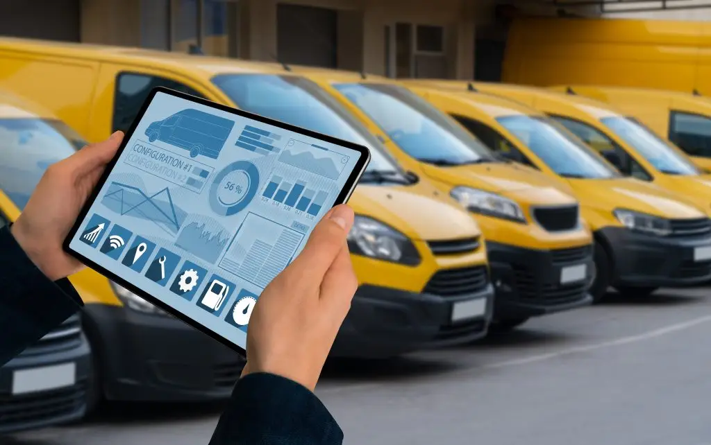 Fuhrparkverantwortlicher überwacht auf einem Tablet die Daten einer Transporterflotte