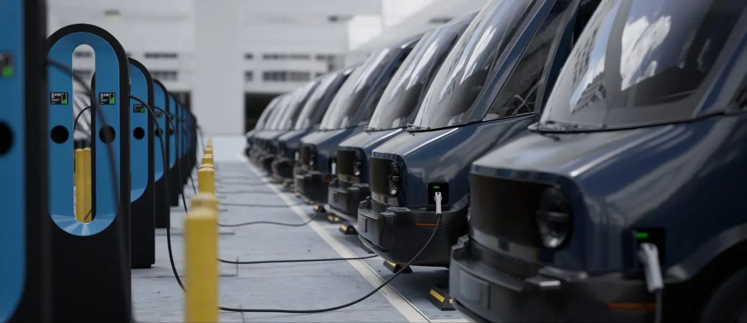 Elektrische Lieferwagen laden nebeneinander an Ladepunkten auf einem Betriebshof