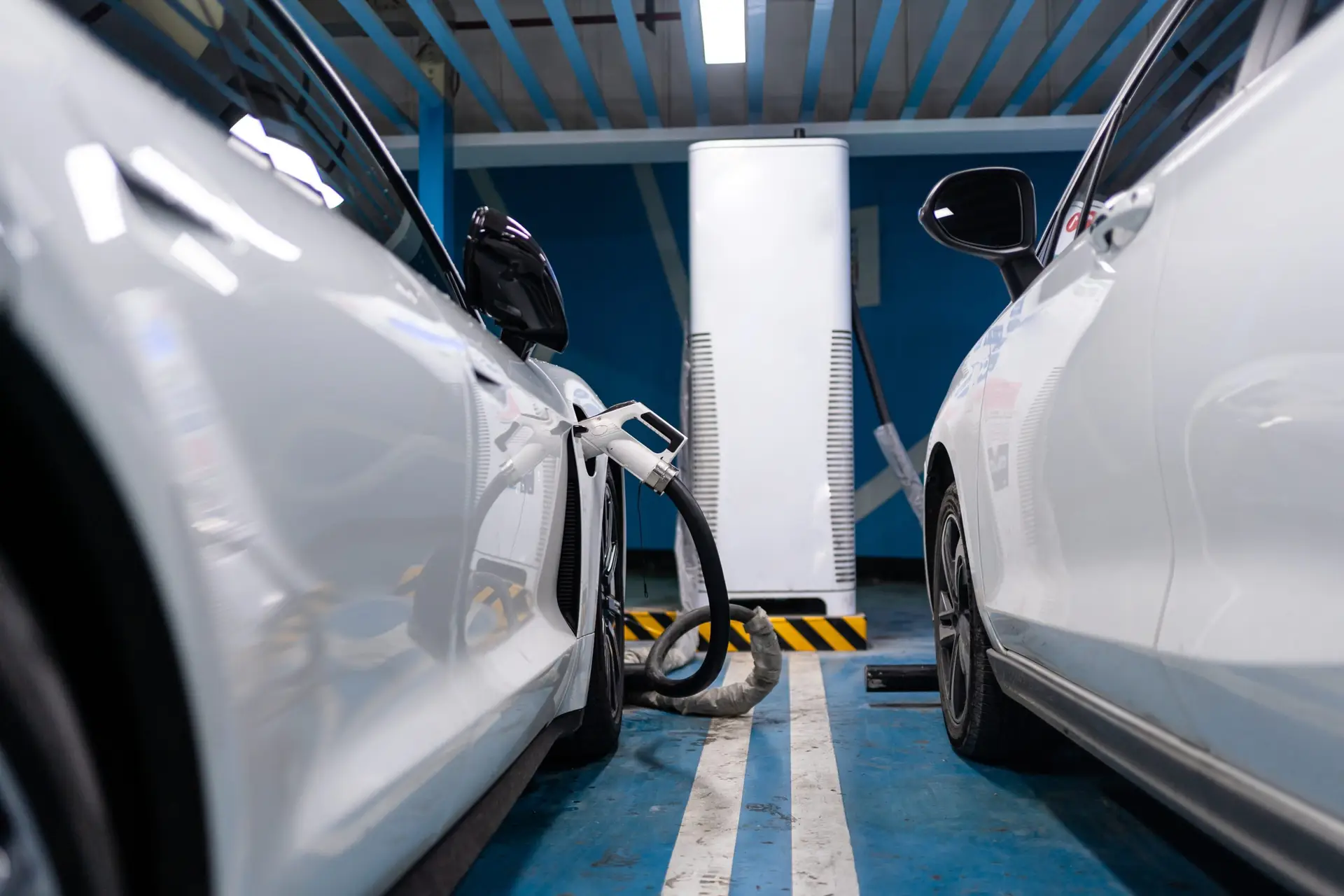 Schnellladesäule zwischen zwei ladenden Elektroautos in einer Tiefgarage