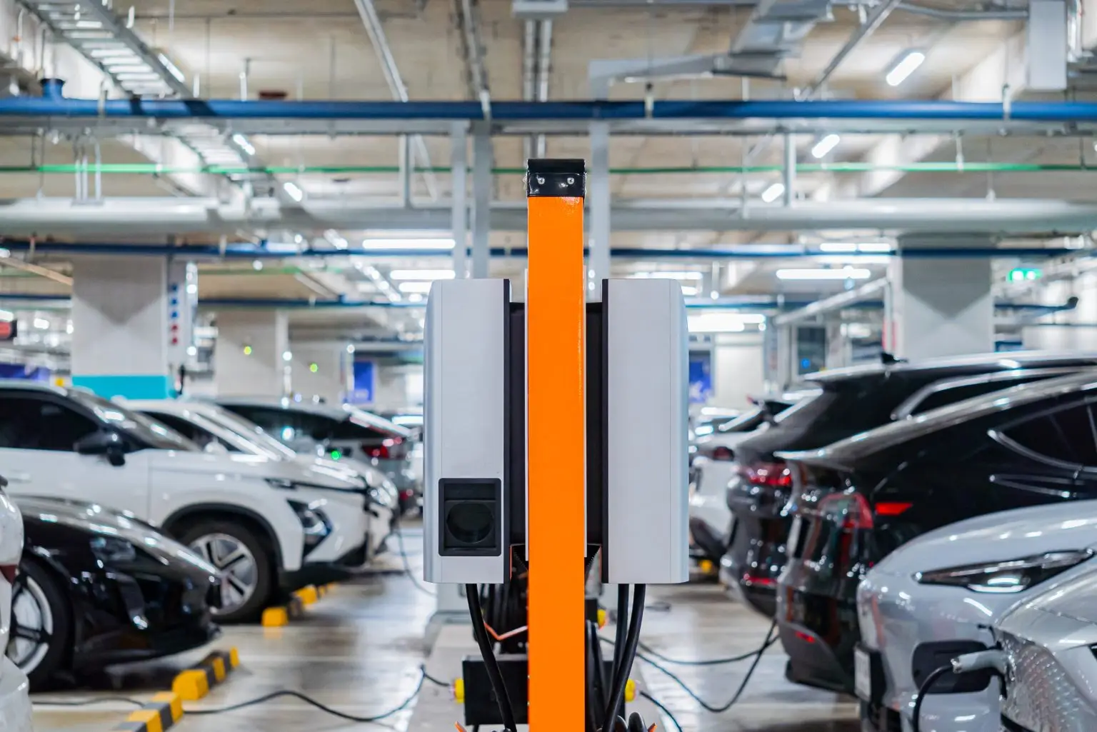 Ladesäule mit zwei Ladepunkten in einer Tiefgarage, daneben mehrere ladende Elektroautos